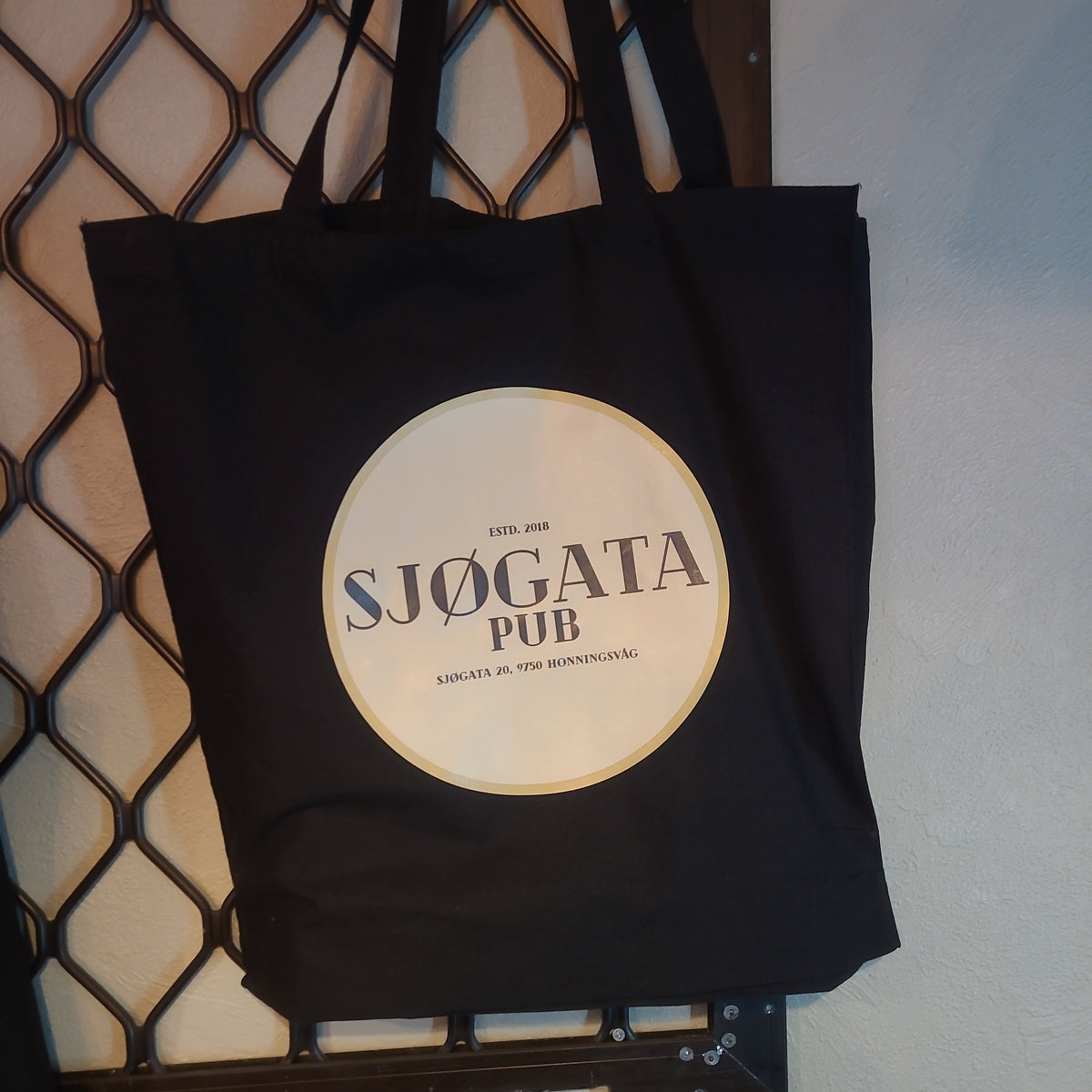 Svart totebag med rund, lys Sjøgata Pub-logo