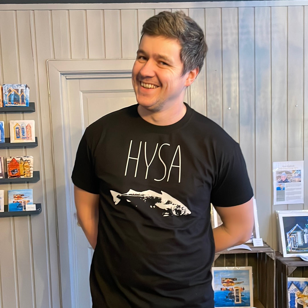 Mann i svart t-skjorte med teksten HYSA og hvitt fisketrykk