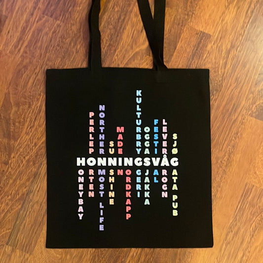 Svart totebag med HONNINGSVÅG og stedsnavn i kryssordmønster i flere farger